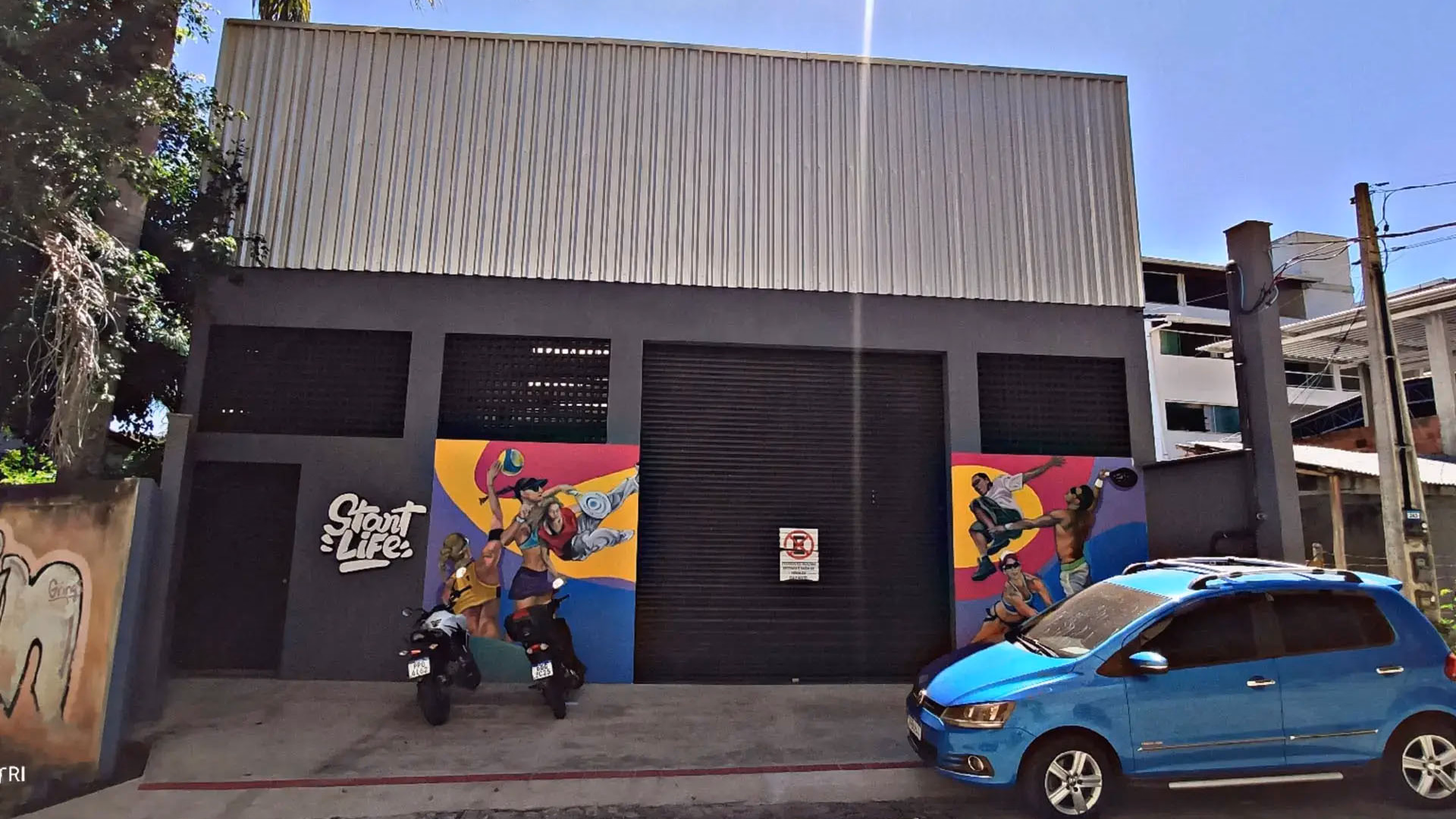 Fachada de galpão comercial com design moderno, pintura urbana artística e portão de enrolar automático